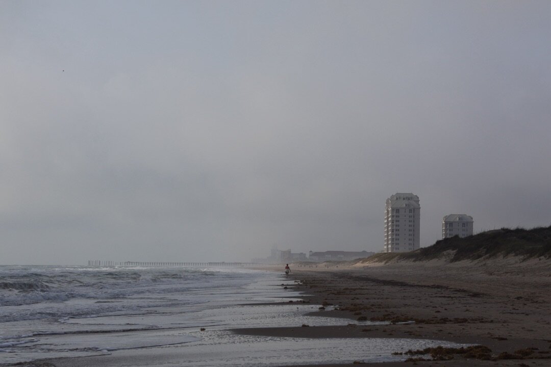 A foggy stretch of beach with distant towers